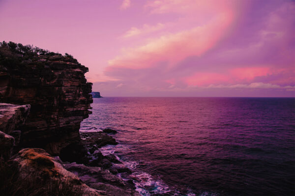 Dramatic pink sunset over Gap Bluff, Watsons Bay in Sydney, with vibrant colors lighting up the ocean horizon.