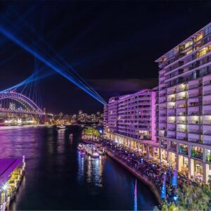 Vivid Sydney lights up Circular Quay in pink including The Bennelong Apartments and Harbour Bridge.