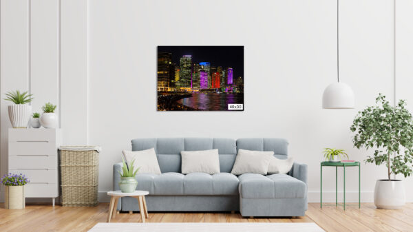 A fine art photograph of Sydney's CBD skyline during Vivid Sydney, taken from Opera Quays. Skyscrapers glow in vibrant purple and red lights, with vivid reflections shimmering across the harbour at night. The image captures the city’s illuminated architecture from a unique perspective, blending light, water, and urban energy.