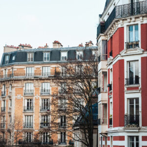 Photograph of classic Parisian apartments in Montmartre with Haussmann-style architecture, iron balconies, and soft natural light on textured facades.