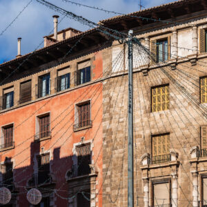 Historic Palma apartments in Mallorca bathed in warm sunlight with Christmas lights in foreground.