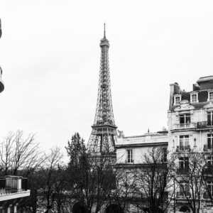 Black and white photograph of the Eiffel Tower viewed from Avenue de Camoëns in Paris, with classic Parisian apartments in the foreground.