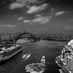 Black and white photograph of Sydney Harbour taken from the rooftop of the historic AMP Building during Open Sydney, showing the Sydney Opera House, The Bennelong Apartments, the Harbour Bridge, a cruise ship near The Rocks, and ferries crossing the water in a timeless, balanced composition.