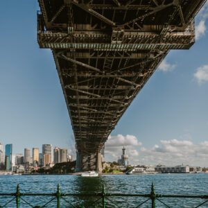 Sydney Harbour Bridge viewed from North Sydney, looking beneath the steel structure towards the Sydney CBD skyline across the harbour.