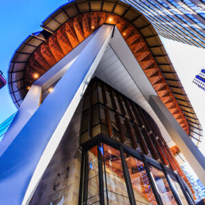 EY Centre Sydney architecture photographed from below, showing dramatic curved rooflines, glass facade and blue evening sky.
