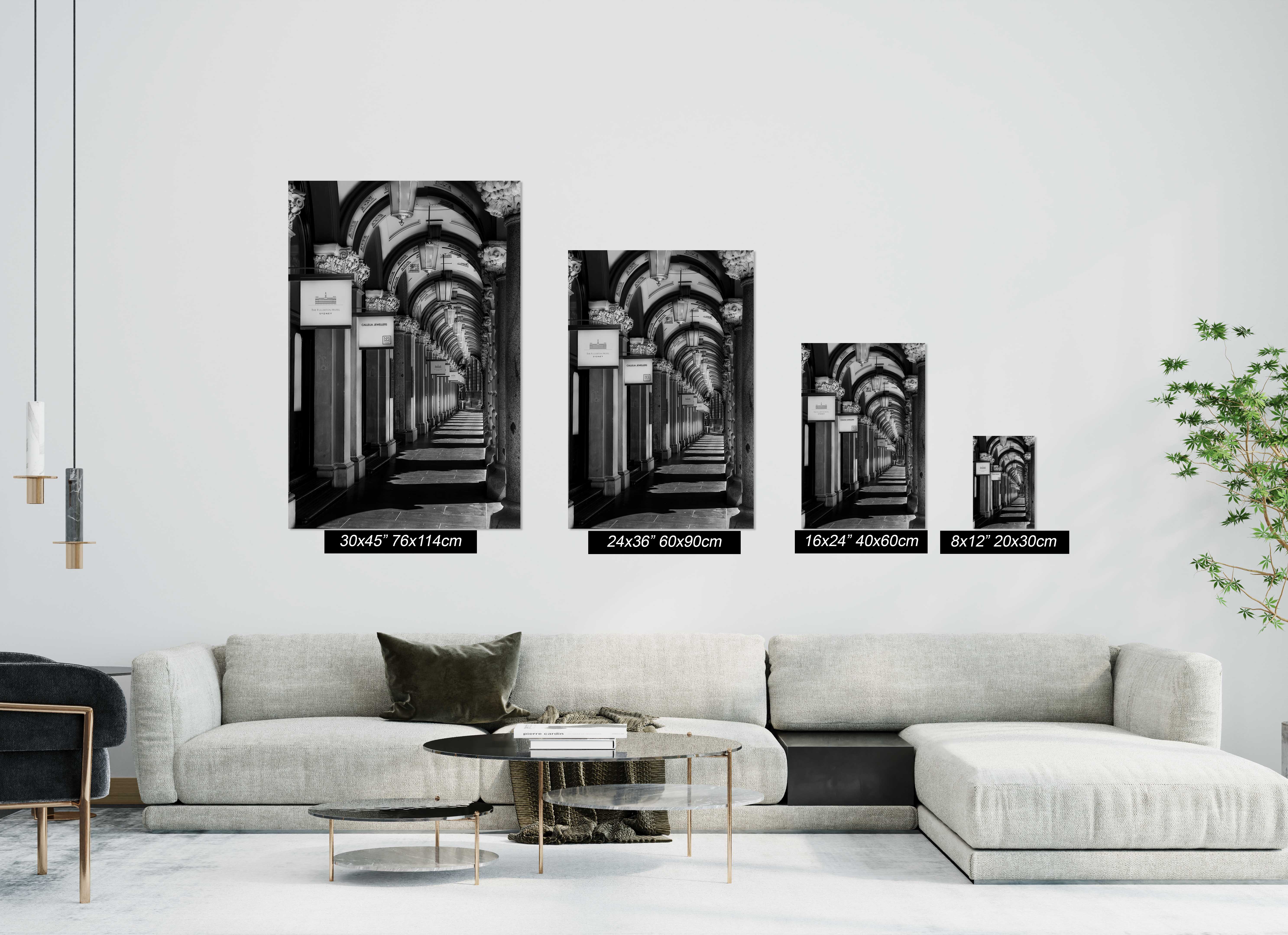 Black and white architectural photography of The Colonnades in Martin Place, Sydney, displayed as four vertical unframed matte paper prints in different sizes above a white sofa in a contemporary living room.