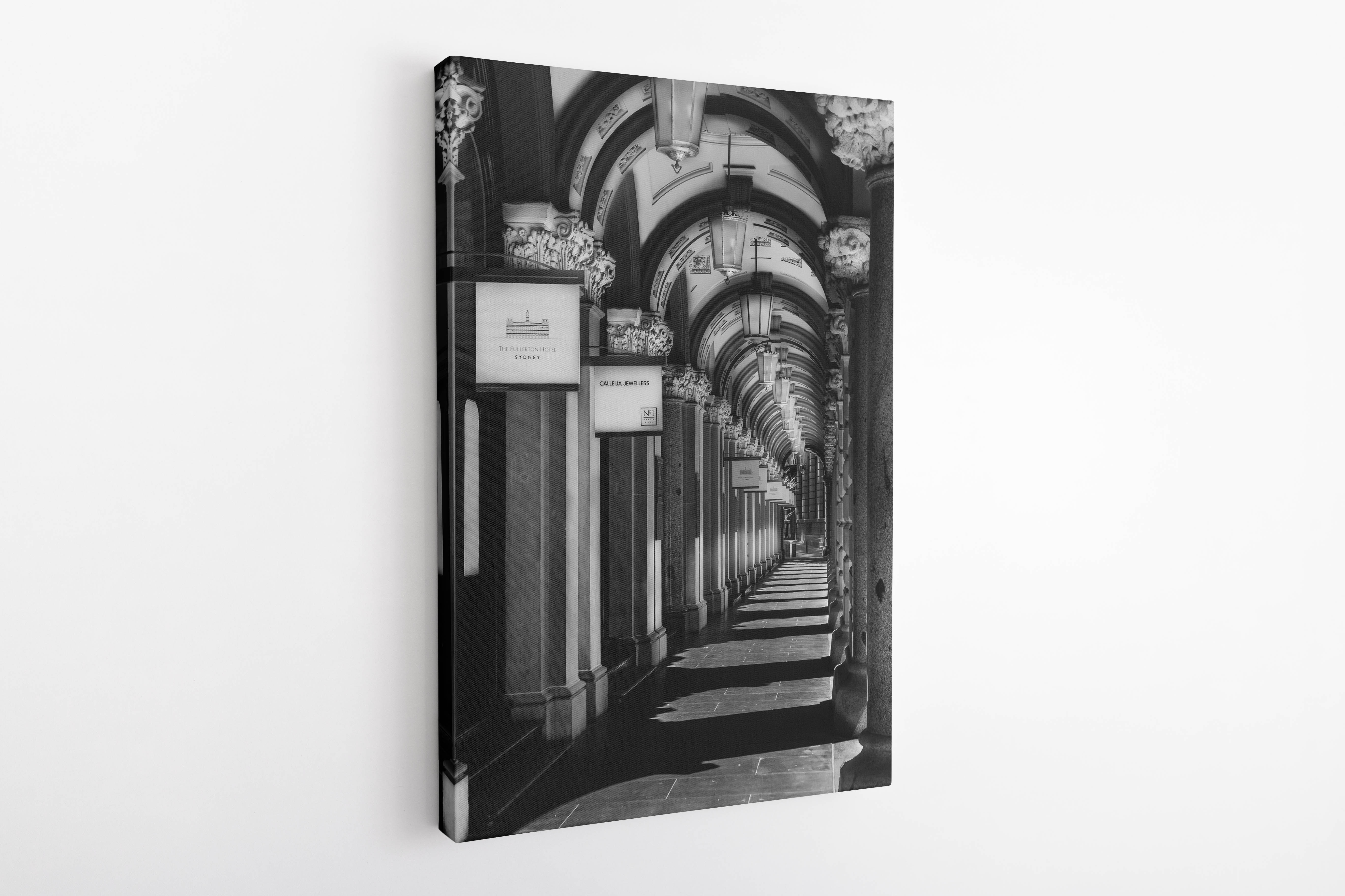 Black and white photograph of The Colonnades in Sydney displayed on a 30 × 45 inch vertical stretched canvas, shown from an angled side view revealing the image wrapping around the canvas edges.