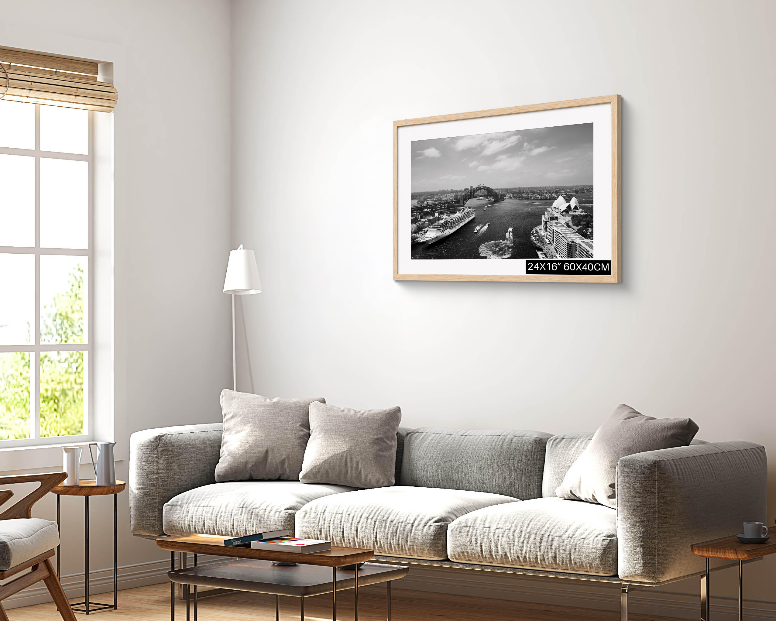 Sydney Harbour black and white photography print showing the Opera House, Harbour Bridge and Circular Quay, displayed in a light wood frame above a modern sofa.