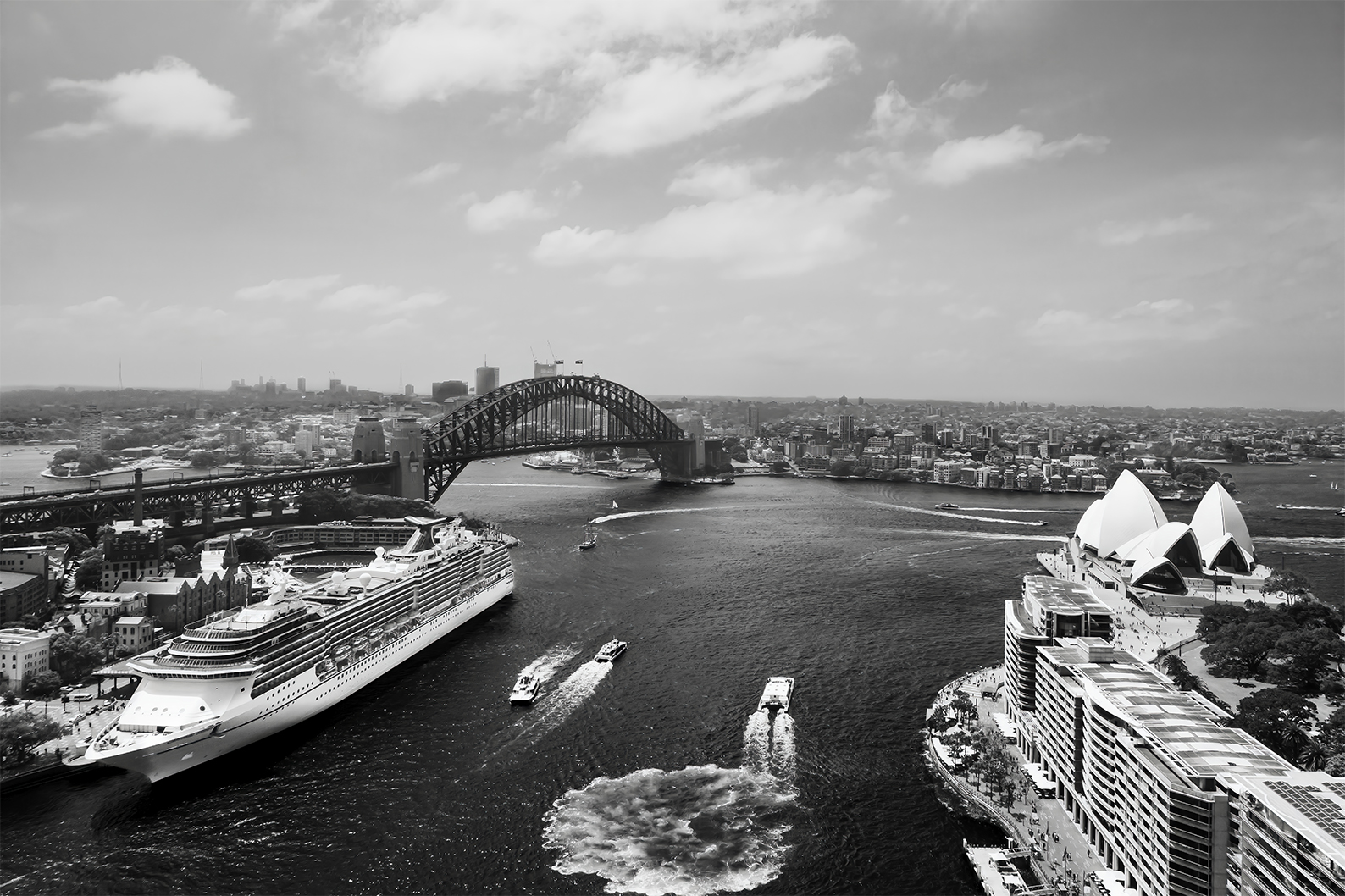 Black and white photograph of Sydney Harbour taken from the rooftop of the historic AMP Building during Open Sydney, showing the Sydney Opera House, The Bennelong Apartments, the Harbour Bridge, a cruise ship near The Rocks, and ferries crossing the water in a timeless, balanced composition.